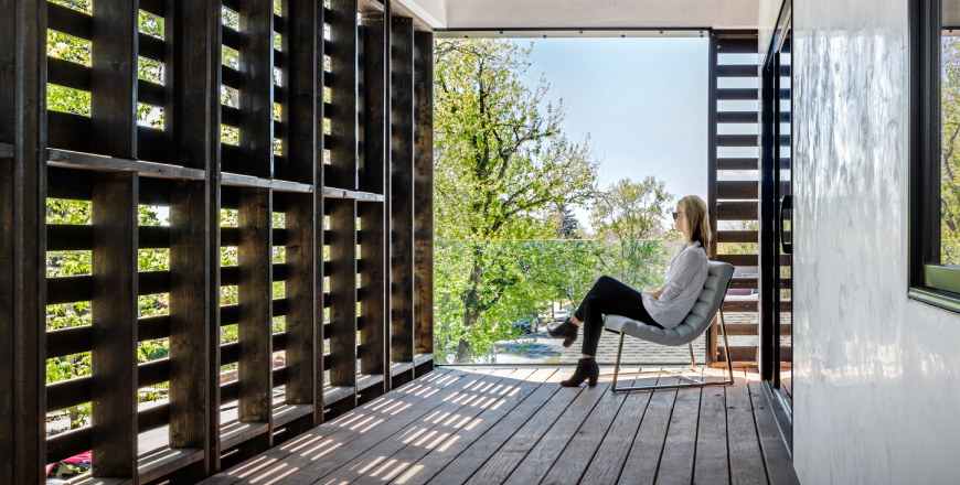 A lady sitting inside a room that has been designed by architects using pallets.